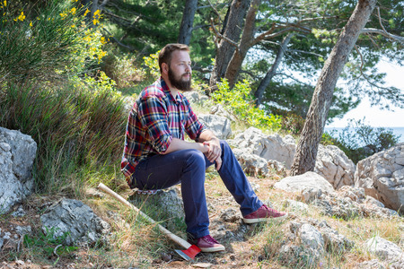 Portrait of an attractive young lumberjack who is resting after cutting a treeの写真素材