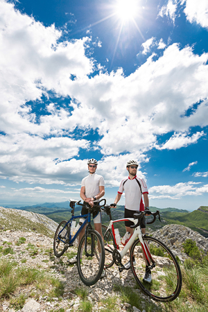 two cyclists stopped in the mountains to enjoy the viewの写真素材
