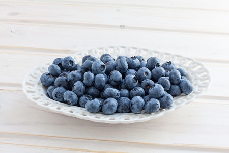blueberries on a white platter on a wooden tableの写真素材