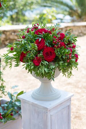flower arrangement in stone bowl with red roses on bollardの写真素材