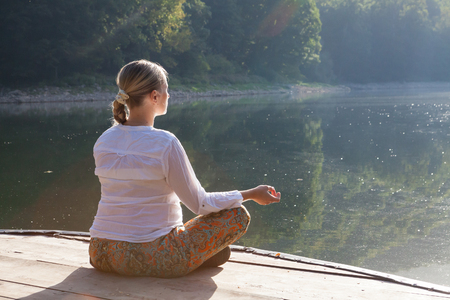 young pregnant woman doing yoga exercises at the lakeの写真素材