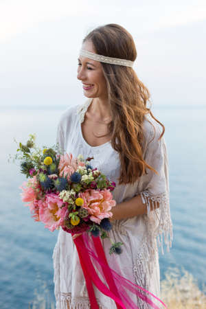 girl with a wedding bouquet boho style, sea backgroundの写真素材