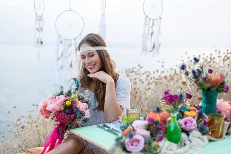 girl with a wedding bouquet boho style, sea backgroundの写真素材