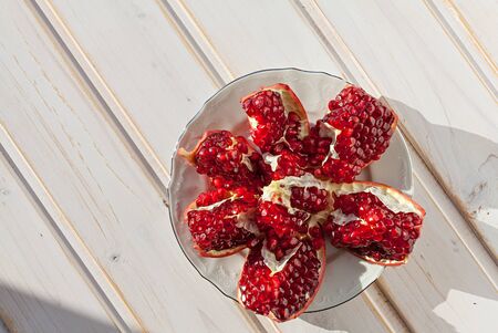 juicy lobules of garnet on plate and wood backgroundの写真素材