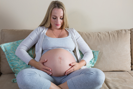 Pregnant woman tenderly stroking her bellyの写真素材