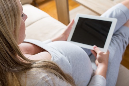pregnant woman spends time on the Internet with the tabletの写真素材