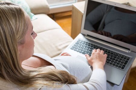 pregnant woman spends time on the Internet with a laptopの写真素材