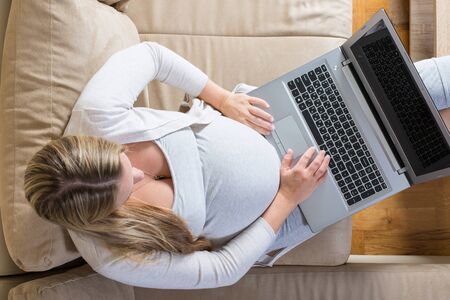 pregnant woman spends time on the Internet with a laptopの写真素材