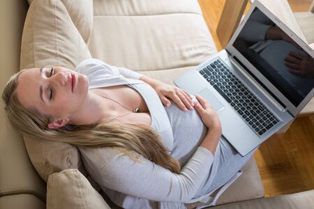 pregnant woman spends time on the Internet with a laptopの写真素材