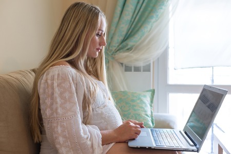 pregnant woman spends time on the Internet with a laptopの写真素材
