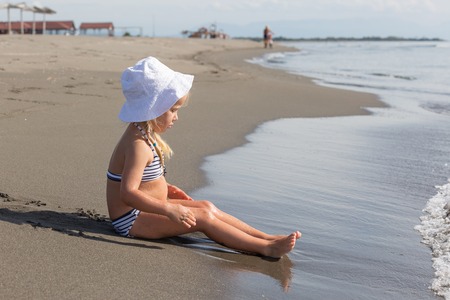 little girl sits at the water's edgeの写真素材