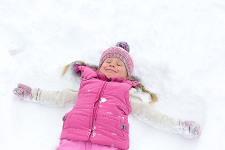 little girl happily playing in the snow outdoorsの写真素材