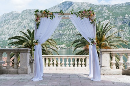 arch for the wedding ceremony, decorated with cloth flowers and greenery, mountains in the backgroundの写真素材