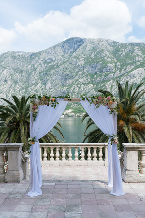 arch for the wedding ceremony, decorated with cloth flowers and greenery, mountains in the backgroundの写真素材