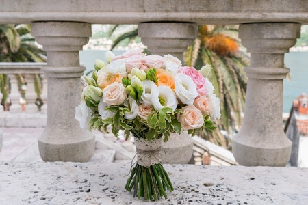 a bridal bouquet of roses, freesia, eustoma standing on a stone backgroundの写真素材