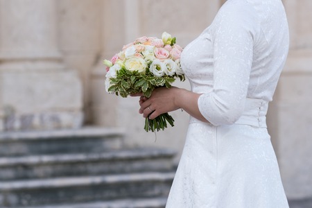 a bridal bouquet of roses, freesia, eustoma that the bride is holdingの写真素材