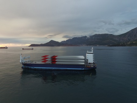 Aerial view of a cargo vessel loaded with rotor blades for wind turbines, taken at sunset