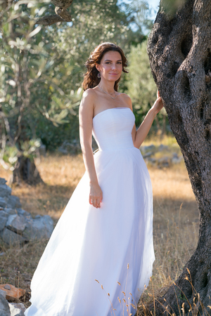 Attractive young woman enjoying her time outside in olive trees with sunset in background.の写真素材
