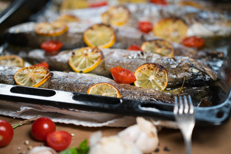 delicious trout fish baked with lemon, tomatoes and spices in baking sheetの写真素材
