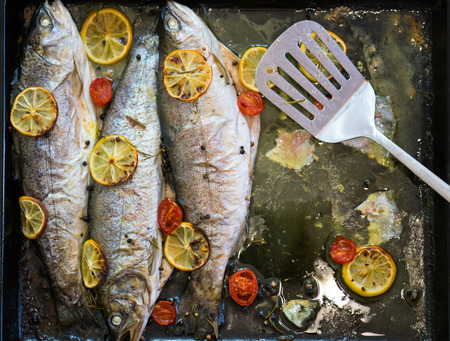 delicious trout fish baked with lemon, tomatoes and spices in baking sheetの写真素材