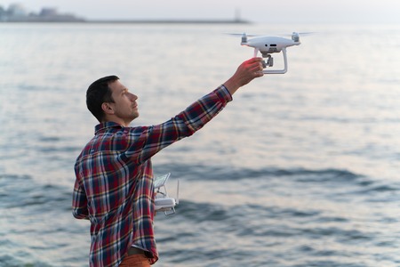 man launches a drone on the beach