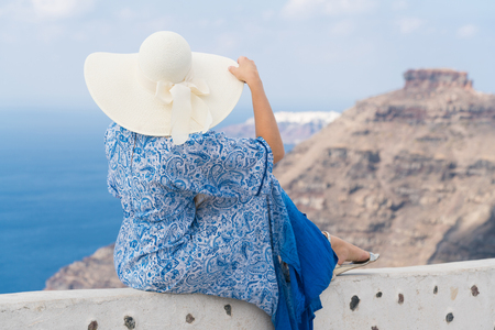 young woman in a white and blue dress enjoys a walk around Santoriniの写真素材