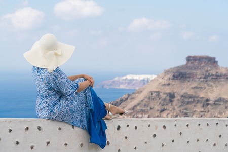 young woman in a white and blue dress enjoys a walk around Santoriniの写真素材