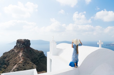 young woman in a white and blue dress enjoys a walk around Santoriniの写真素材