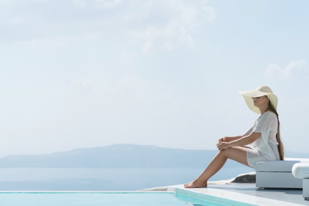 young woman enjoying a magnificent view of Santorini near the pool.