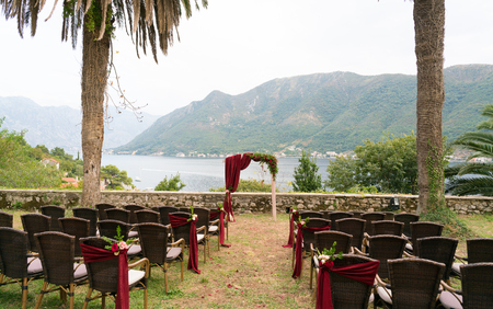 arch and chairs decorated with fresh flowers in dark red tones for the wedding ceremonyの写真素材