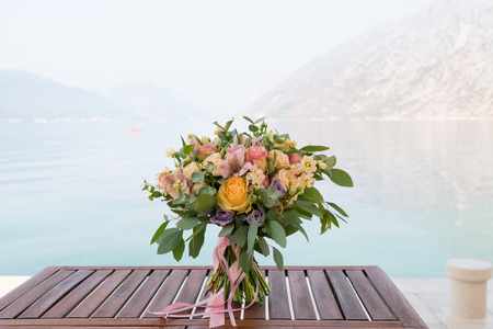 pink and peach wedding bouquet is on the tableの写真素材