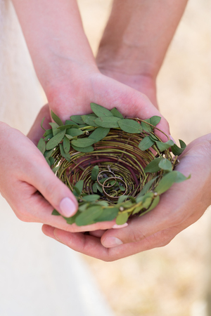 wicker plate with wedding rings in the hands of the newlywedsの写真素材