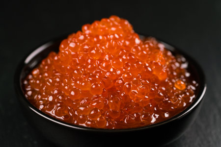 Red Caviar in a black bowl over black background.の写真素材