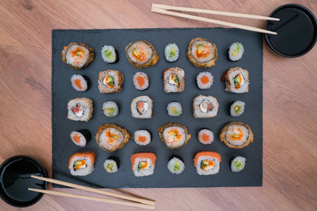 black slate board with sushi with bowls with soy sauce and chopsticks for sushiの写真素材