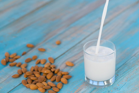 Organic almond milk is poured into a glass on blue wooden backgroundの写真素材