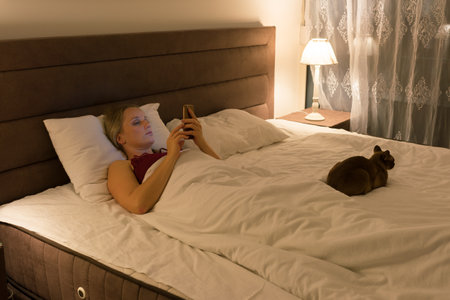 woman in bed before going to sleep with phone in handの写真素材