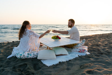 attractive couple by the sea with wine and fruit enjoying each others companyの写真素材