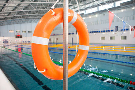 Orange lifebuoy near public swimming pool On a blurred background, a swimming pool is visibleの写真素材