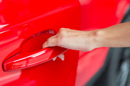 Woman hand on open the new red car door background Close-upの写真素材