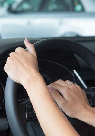 The hand of a girl with a stylish manicure lies on the handlebars in a saloon car. Close-upの写真素材