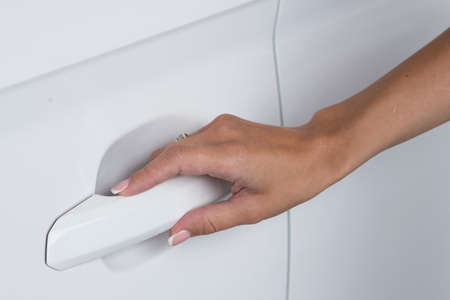 Woman hand on open the new white car door background Close-upの写真素材