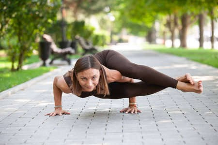 Pretty woman doing yoga exercises in the park Practicing of yoga outdoors. Portrait of gorgeous young woman practicing Yoga - relax in natureの写真素材