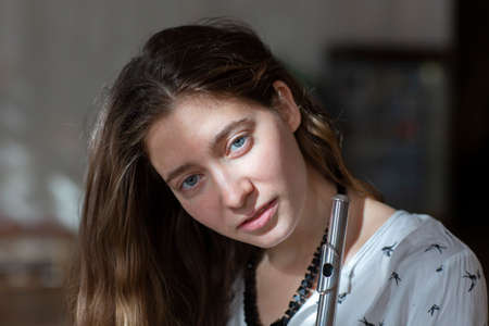 A beautiful woman posing while playing on a flute Flute in hands of girl during the concert. Genre portrait of young beautiful girlr Close-upの写真素材