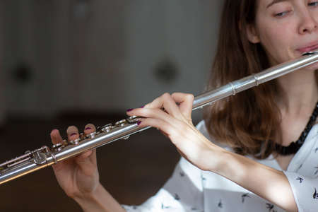 A beautiful woman posing while playing on a flute Flute in hands of girl during the concert. Genre portrait of young beautiful girlr Close-upの写真素材