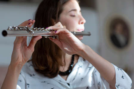 A beautiful woman posing while playing on a flute Flute in hands of girl during the concert. Genre portrait of young beautiful girlr Close-upの写真素材