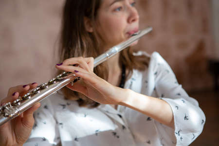 A beautiful woman posing while playing on a flute Flute in hands of girl during the concert. Genre portrait of young beautiful girlr Close-upの写真素材