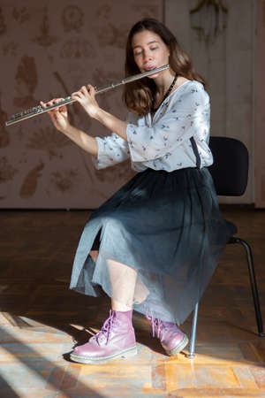 A gorgeous young woman sitting and playing the flute Close-upの写真素材