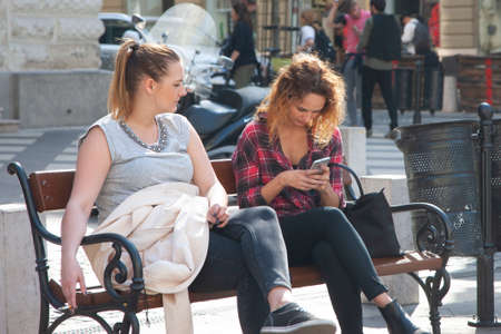 Budapest, Hungary - April 5, 2018: Two Young Women on a Bench at Park Genreのeditorial素材