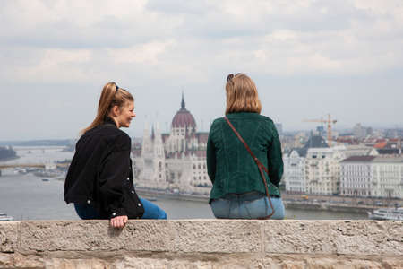 Budapest, Hungary - April 10, 2018: Two Young Women on a Bench at Park Genreのeditorial素材