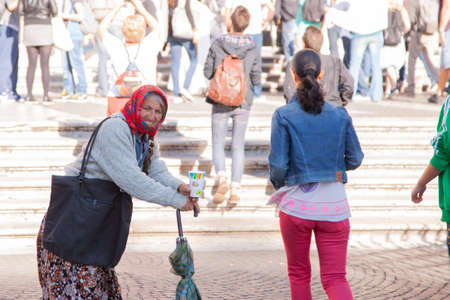 Rome, Italy, October 9, 2011: Older woman asking for alms at the entrance to a Catholic church Genre